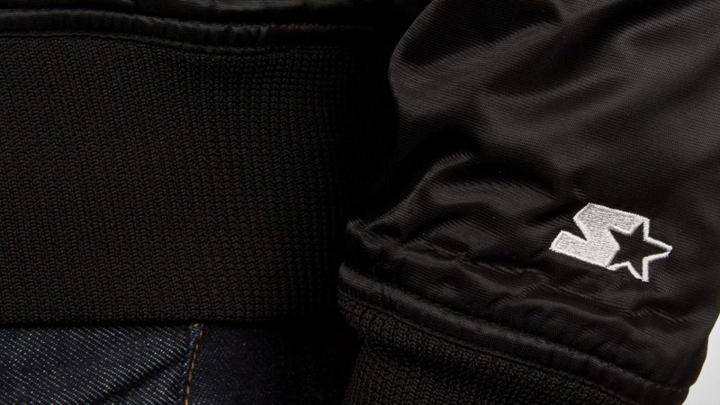 Vintage black starter jacket with star logo detail, perfect for retro style and warmth.