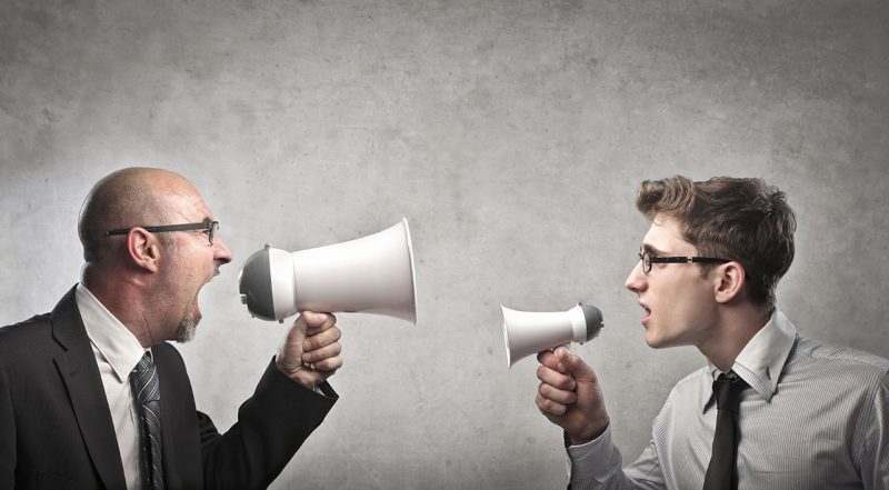 Two men arguing with megaphones, demonstrating assertive communication.