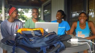 Kids studying outdoors, smiling and enjoying group learning with a laptop.