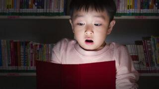 Child reading a book in a library about classic fairy tales.