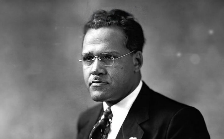 African-American automobile manufacturer founder in a formal suit and glasses.