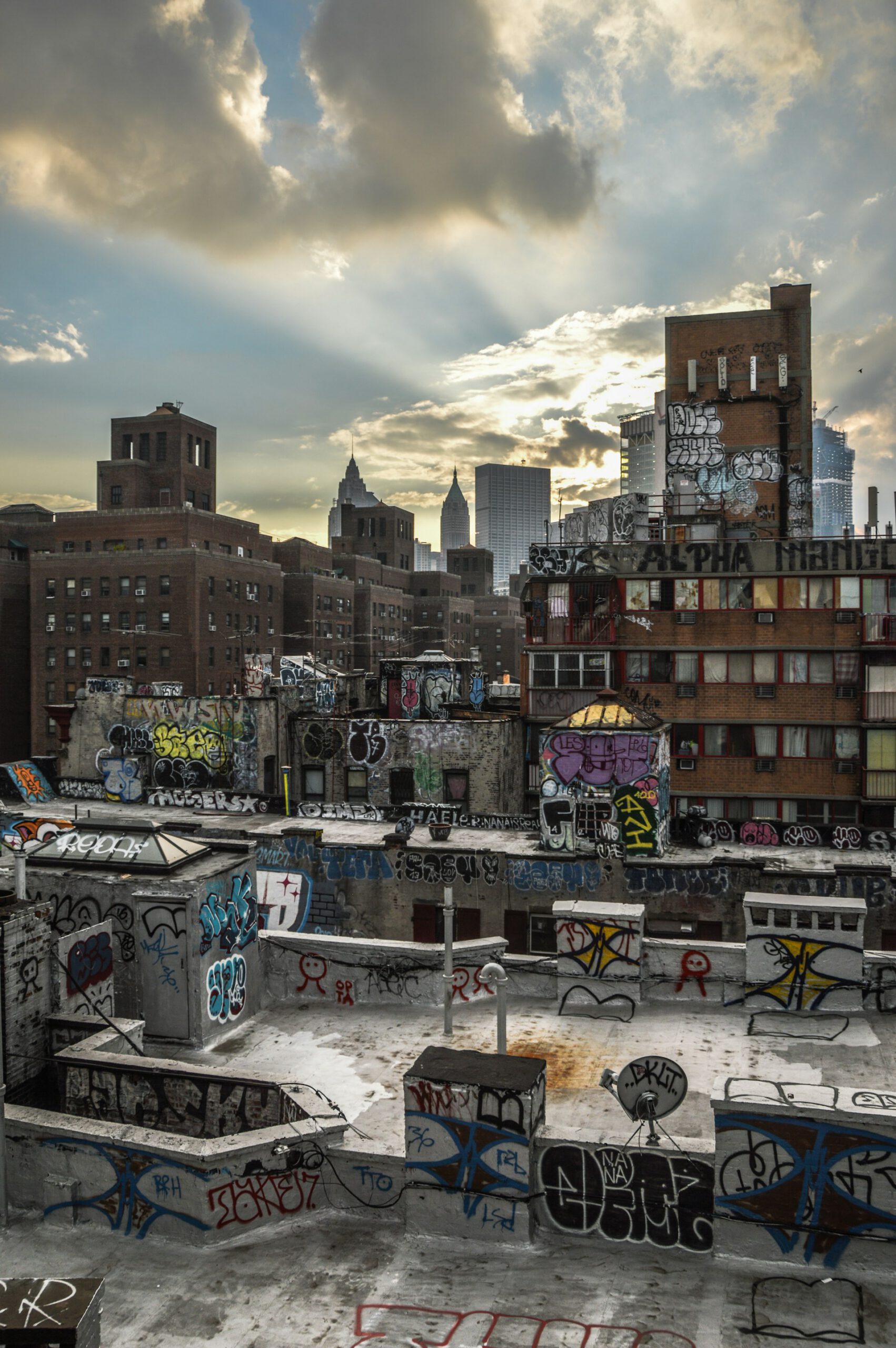 New York City rooftops covered in graffiti &mdash; the earliest form of hip-hop art &mdash; with dramatic sunlight streaming through clouds over the skyline